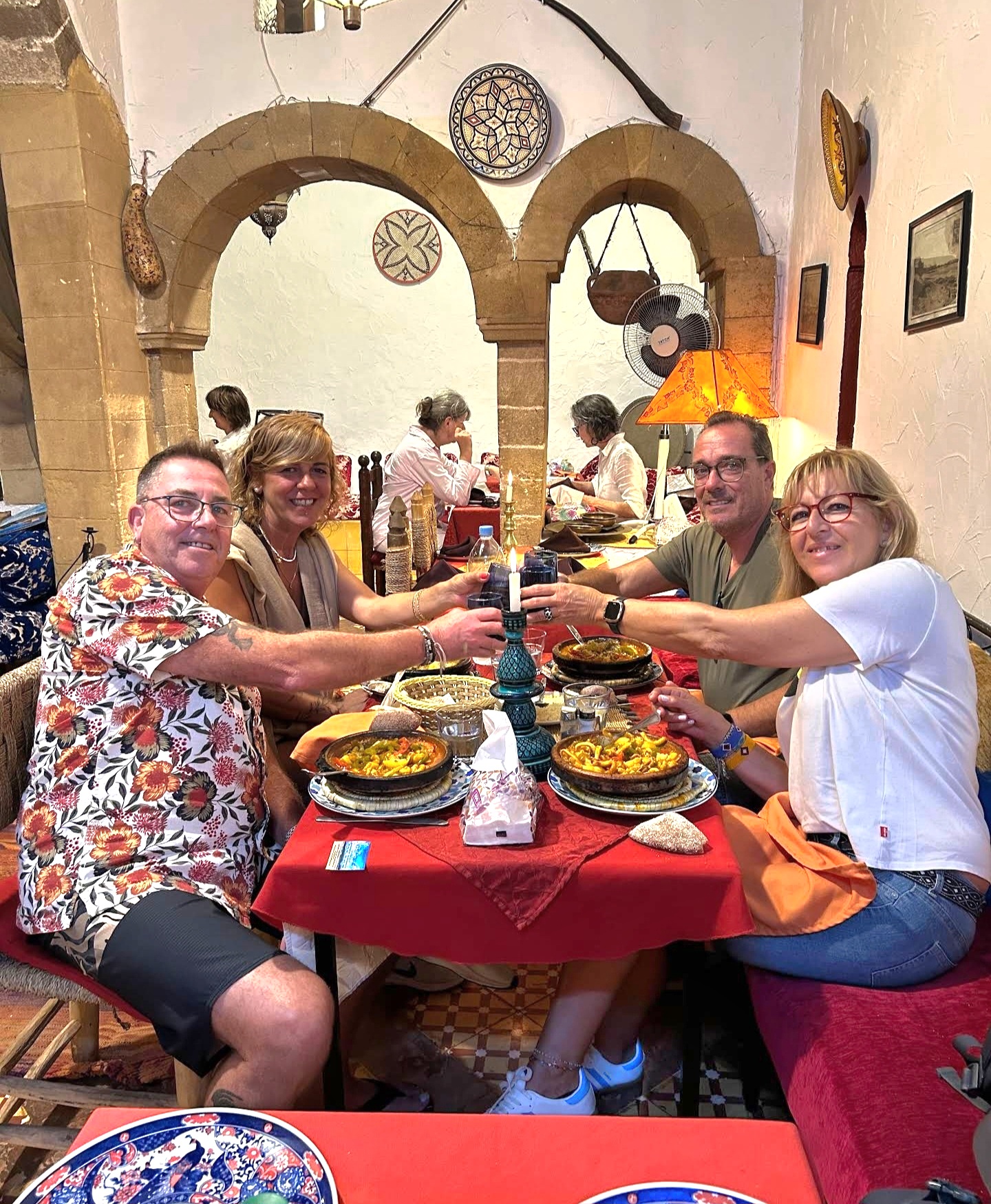 Guests raising glasses around a table of Moroccan dishes